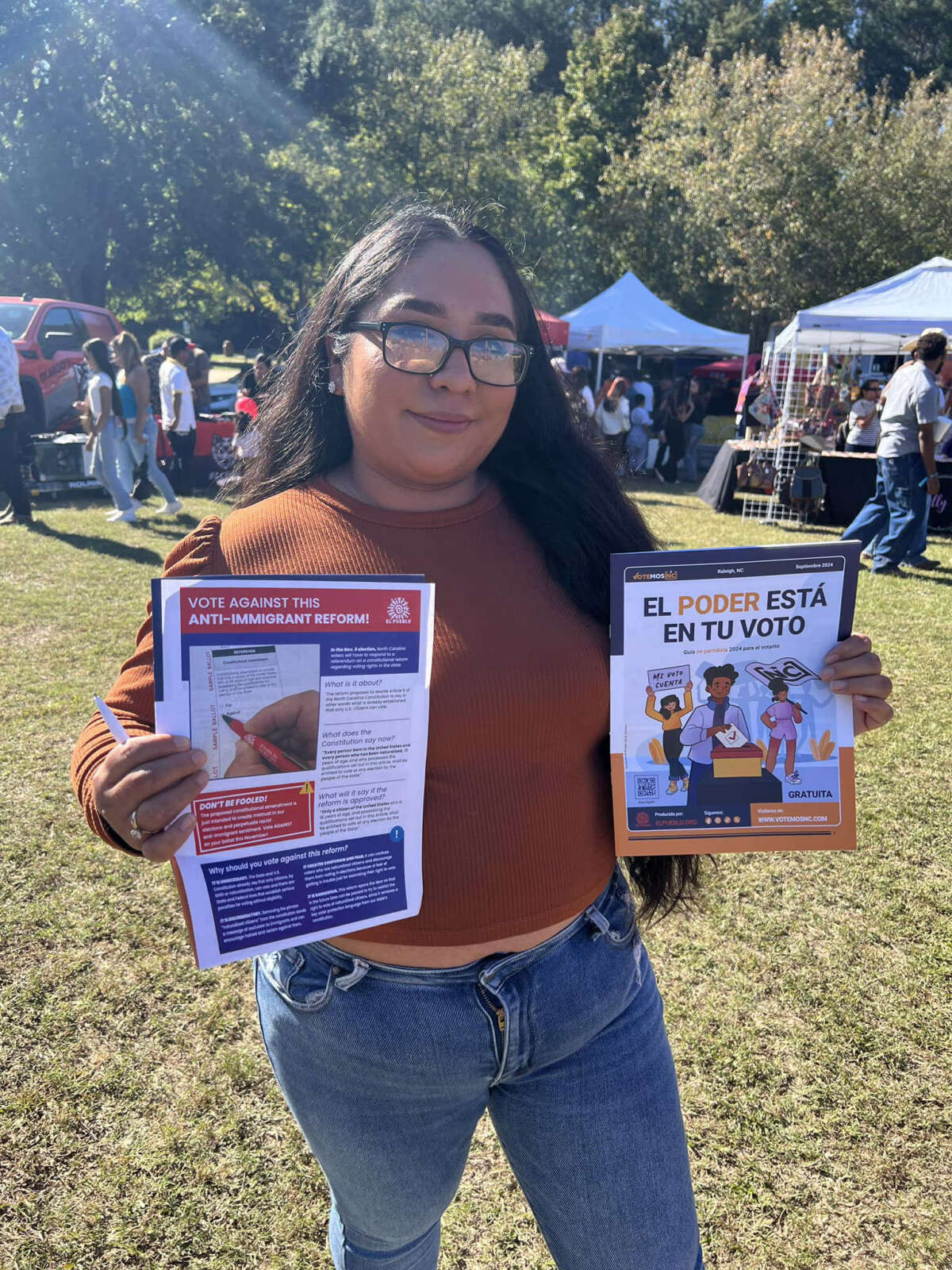 El Pueblo member holds two election tipsheets, one in Spanish and the other in English, at the 13th celebration of Radio La Grande NC in Lake Benson Park in Garner, October 13, 2024. 